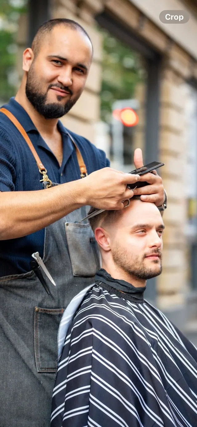 A barber checking a cut outside the shop